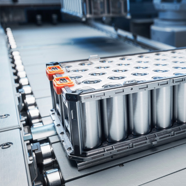 Close-up of a rack of cylindrical battery cells on a production line